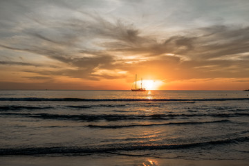 Sailboat on the sea with  big waves  and colorful sunset background