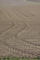 Traktorspuren im braunen Ackerboden