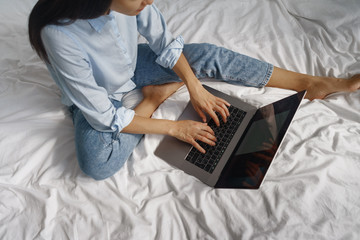 young woman working on laptop in bed