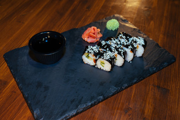 A set of sushi. Philadelphia roll, California, unagi, black dragon with fresh ingredients on a black background. The sushi menu. Japanese cuisine. Ginger and wasabi. Soy sauce. Sesame