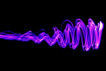 Long exposure photograph of neon pink and purple colour in an abstract swirl, parallel lines pattern against a black background. Light painting photography.
