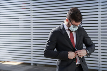 Businessman wears mask to prevent coronavirus. Excellent photo to express the concept of responsibility. Modern architecture on the background