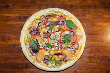 Italian pizza with mushrooms and herbs on a wooden table