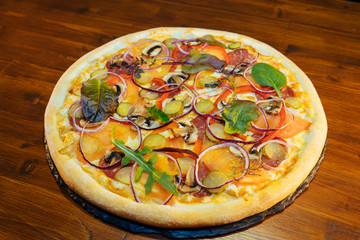 Italian pizza with mushrooms and herbs on a wooden table
