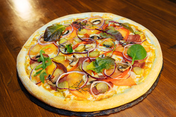Italian pizza with mushrooms and herbs on a wooden table