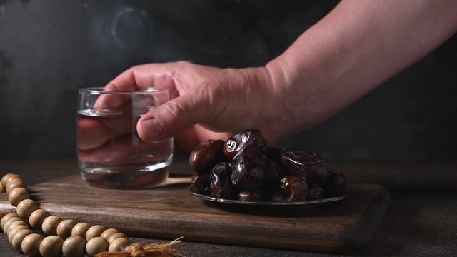 Muslim takes date and then glass of water. Prayer. Iftar starts. Ramadan. Eid Mubarak. Religious tradition.