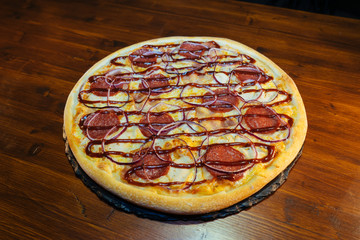 Italian pizza with sausage products on a wooden table