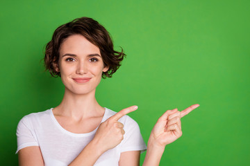 Photo of attractive lady wavy hairdo direct fingers side empty space demonstrating cool shopping prices novelty wear casual white t-shirt isolated green color background