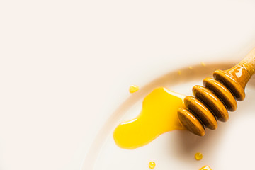 Naklejka premium The honey spoon is on a white plate. Honey drips from the spoon onto the plate 