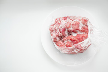 A plate of frozen meat on it. The pieces of meat were covered with frost from the temperature difference