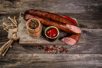 Obraz na płótnie Canvas Smoked sausage on a wooden rustic table product from organic farm, produced by traditional methods. banner menu recipe place for text