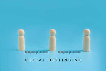 Wooden dolls on blue background with distancing and measure scale. people practice social distancing to protect from COVID-19 coronavirus spreading. Social distance preventing infection concept.
