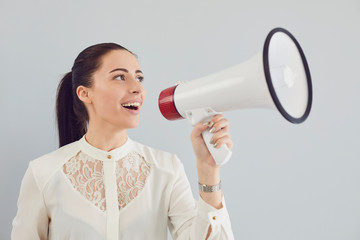 A woman in a white shirt in a bullhorn on a gray background.