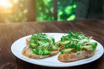 sandwiches with avocado and cressalate microgreens on a white plate on a window background. healthy diet. feed option. vegetarianism.