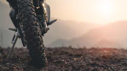 Part of a motocross wheel on a mound, the background is a mountain with sunrise.copyspace for your...