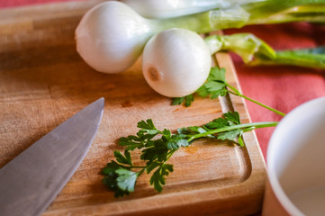 onions and parsley on a wooden cutting board ready to be chopped