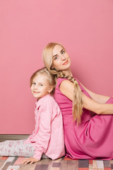 mother with daughter in pink clothes on a pink background