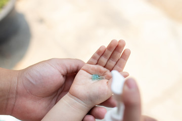 Naklejka premium Dad cleaning baby hands with alcohol gel. protected virus concept.