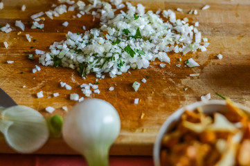 minced onions with mezzaluna on cutting board close up