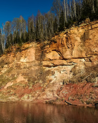 Impressive view of high red rock stone cliffs next to Gauja river in Vidzeme, Latvia, at sunny spring day