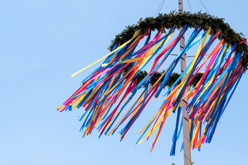 colourful maypole blowing in the wind with a blue sky background  - obrazy, fototapety, plakaty