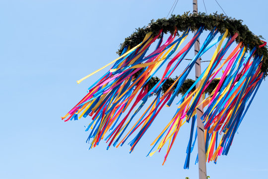 colourful maypole blowing in the wind with a blue sky background 
