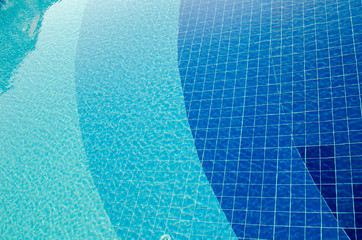 Open swimming pool. Pure clear water. Blue tile at bottom. Reflections Metal railing. Close-up. Summer holiday concept. Vacation backdrop. Sunny day. Sunlight. Selective focus. Copy space.