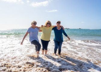 Group of three senior women walking having having fun on beach. Friendship and healthy lifestyle