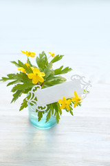 yelllow wild flowers and empty card on white wooden background. spring season concept. copy space.