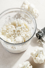 Making raw grated cauliflower in food processor for vegetable pizza crust or rice top view