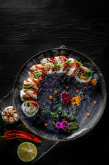 sushi roll with cream cheese, cucumber and eel in plate on black wooden table background
