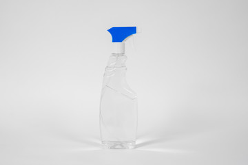 Plastic bottle with blue atomizer and transparent liquid or gel inside standing on white background.