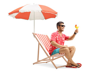 Young man making a toast with a cocktail under umbrella