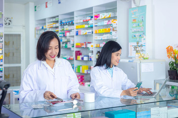 Fototapeta na wymiar Two Asian pharmacists working in a pharmacy drugstore. Health care and medical concept.