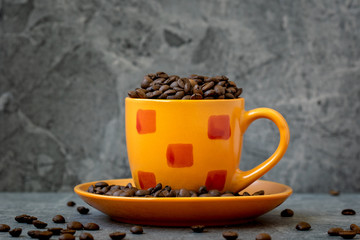 Orange cup filled with roasted coffee beans