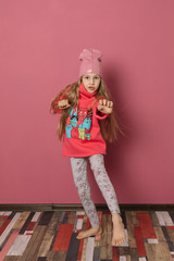 Little girl in pink clothes on a pink background