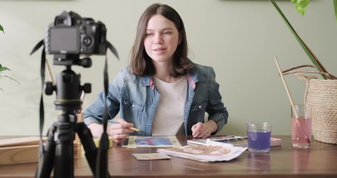 Artist, teenage girl, draws and records on video camera for his blog