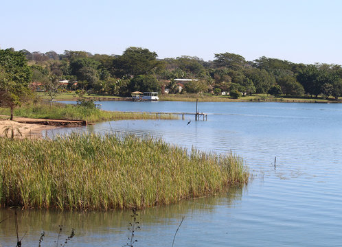 Grande lago azul, com vegeta&ccedil;&atilde;o e resid&ecirc;ncias na margem