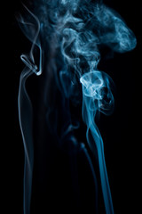 white smoke dances in different shapes on a black background