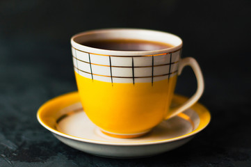 Yellow cup with coffee without foam on a dark background