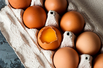Chicken eggs in a tray on a dark background, visible yolk