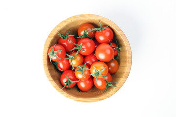 Red ripe cherry tomato with stem wooden bowl on white background top view