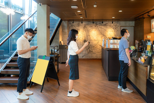 Three Asian People Wearing Mask Standing Distance Of 6 Feet From Other People Keep Distance Protect From COVID-19 Viruses And People Social Distancing For Infection Risk At Coffee Cafe..