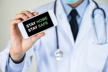 Doctor hand holding mobile phone with stay home stay safe message for stop coronavirus disease