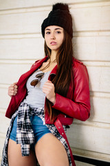 Hipster girl with red jacket posing on her bike on the street