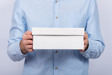 Male hands holding a cardboard box. Front view. Express delivery. Postman brought parcel