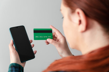 A cute young girl an online application client makes purchases of clothes or food without leaving home. Pay online utility bills, bills via smartphone and credit card