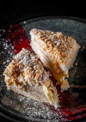 Layered cake with cream Napoleon in plate on wooden table background