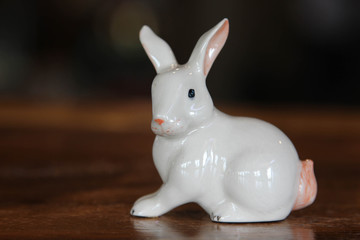Statue of a white rabbit doll on the wooden table.