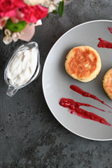 cheese pancakes with jam. on a gray background with flowers